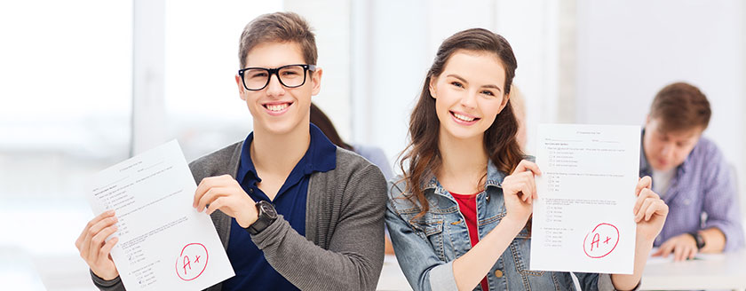Students At Desk Showing A+ Grades on Papers